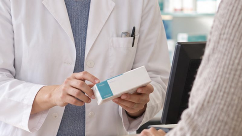 Apothekerin reicht eine Arzneimittelpackung über den Tresen