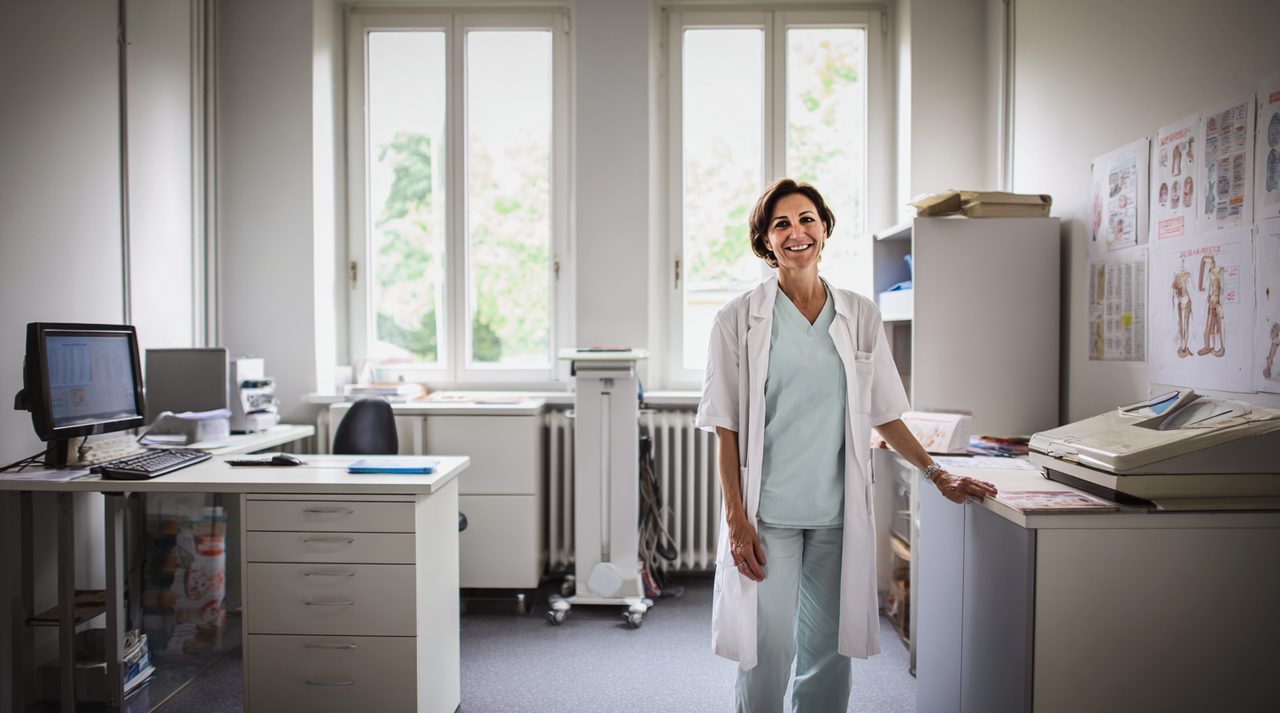 Lächelnde Ärztin in ihrem Sprechzimmer